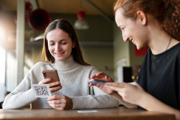 Deux femme dans un bar payent avec un QR code de paiement avec un lien court